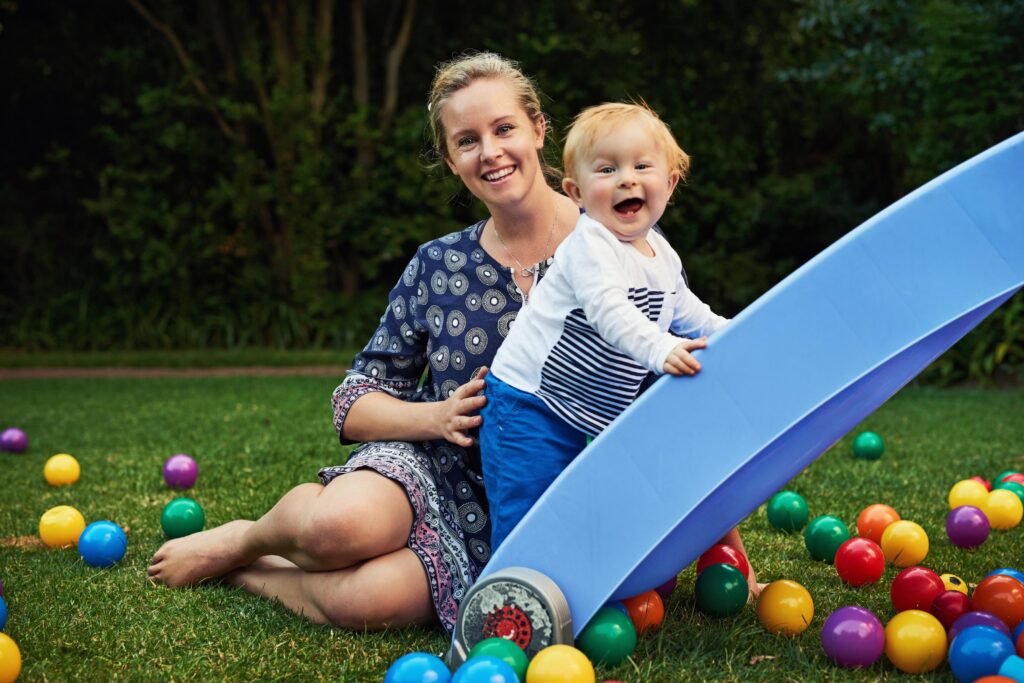 Smiling Woman with Red Haired Toddler playing Outdoors