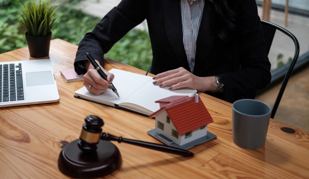 Real Estate Law concept. Gavel on sounding block in hand's female judge at a courtroom, working for the insurance compensations. report the case on table in modern office.