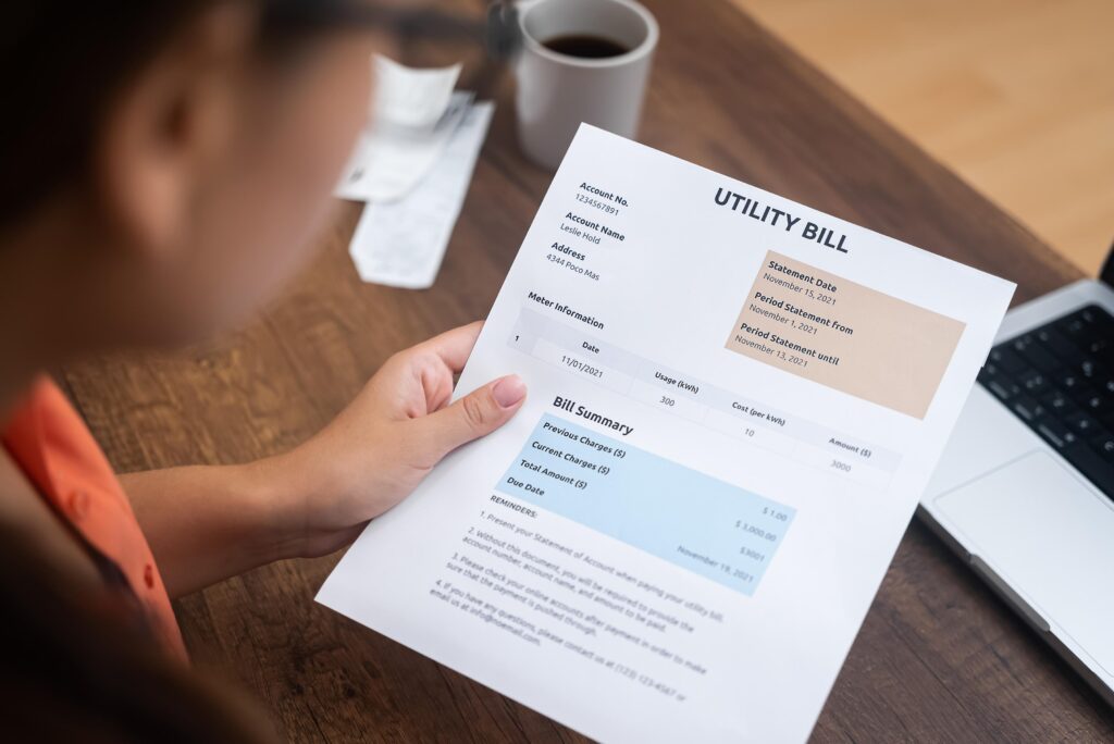 Woman with payment receipts making count of household at home on wooden table with cup and laptop