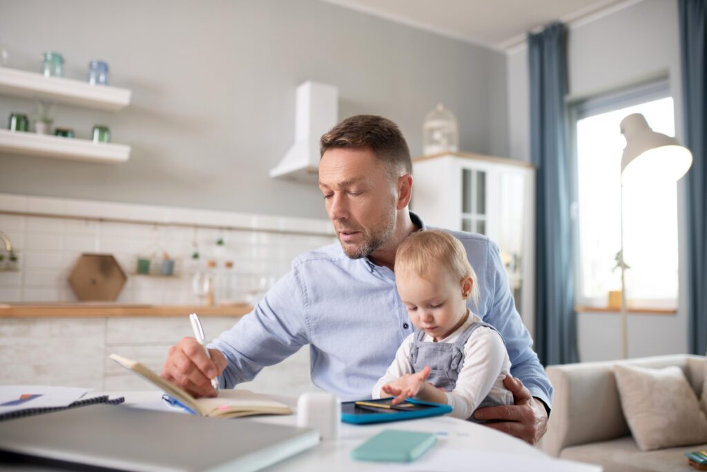 Man in a blue shirt holding his kid and making notes